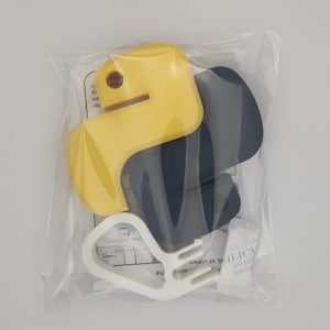 K&ouml;nnte beinhalten: Ein Satz mit drei T&uuml;rstoppern in Gelb, Grau und Wei&szlig;. Die T&uuml;rstopper sind aus einem weichen, flexiblen Material gefertigt und sollen verhindern, dass T&uuml;ren zuschlagen.