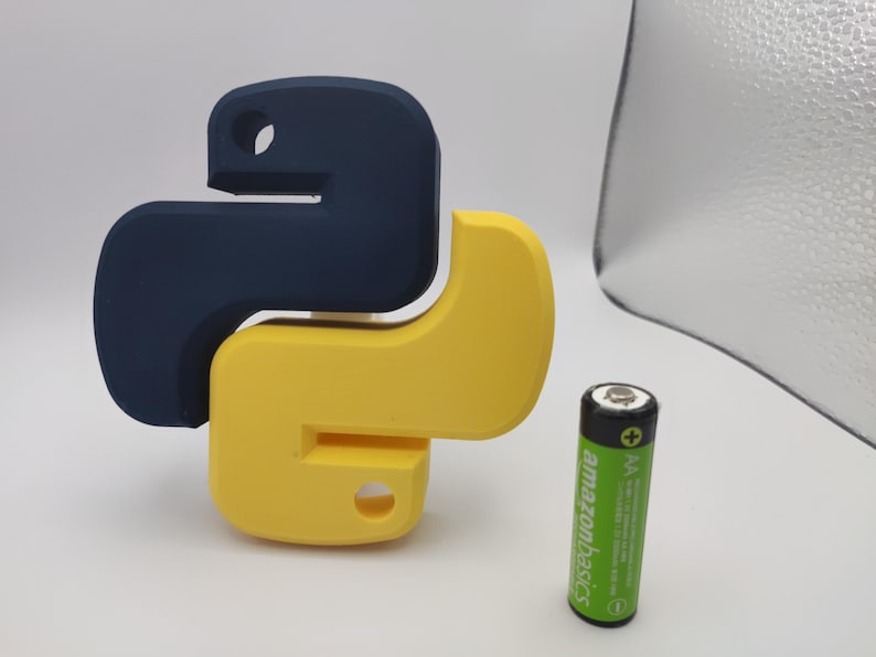 K&ouml;nnte beinhalten: Ein 3D-gedrucktes Python-Logo in Blau und Gelb. Das Logo ist schlangenf&ouml;rmig und etwa so gro&szlig; wie eine AA-Batterie.