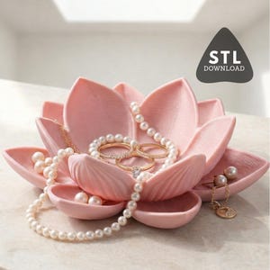 Può includere: Un portagioie a forma di fiore di loto rosa con anelli, collane e gioielli di perle. Il portagioie ha più scomparti per organizzare i gioielli. L'immagine include anche una grafica che dice "STL DOWNLOAD".