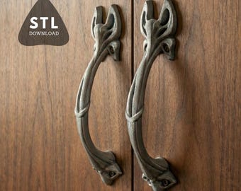 May include: Two decorative, grey cabinet handles with a curved design, mounted on a wooden cabinet. The handles feature a detailed, floral-inspired pattern. The image also includes a logo that says "STL DOWNLOAD".