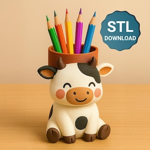 Op de afbeelding: Een grillige potloodhouder in de vorm van een zittende koe, met kleurrijke potloden. De koe is wit met zwarte vlekken, bruine hoeven en een lachend gezicht. De potloodhouder is een bruine cilinder. De tekst "STL DOWNLOAD" is inbegrepen.