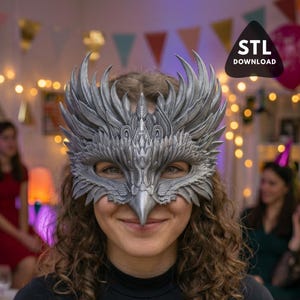 Puede incluir: Una máscara plateada, con un diseño intrincado en forma de cabeza de pájaro, con patrones de plumas detallados. La máscara cubre los ojos y la nariz, con un pico prominente. La imagen incluye el texto "STL DOWNLOAD" en un triángulo negro.
