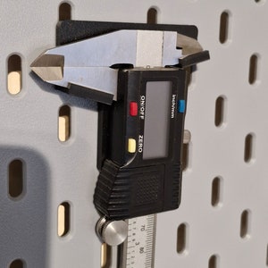 May include: A black digital caliper with a silver ruler and a knob. The caliper has a digital display that reads "inch/mm" and has buttons for "ON/OFF" and "ZERO".