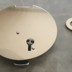 Könnte beinhalten: Ein glänzendes, silberfarbenes, kreisförmiges Schloss mit Schlüsselloch und einem kleinen, passenden Schlüssel. Das Schloss hat eine flache Oberfläche mit einem kleinen Loch in der Nähe des Schlüssellochs. Der Schlüssel ist ein einfaches, flaches Design mit der eingravierten Zahl 3.