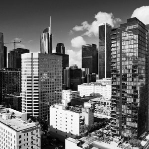 Puede incluir: Vista aérea en blanco y negro de un horizonte urbano con edificios altos. Los edificios son mayoritariamente modernos y tienen un diseño elegante y contemporáneo.