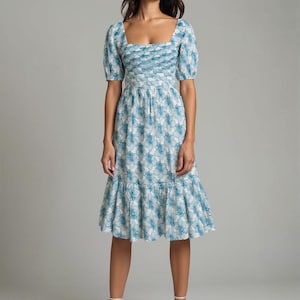 May include: A midi-length dress featuring a square neckline and short puff sleeves. The garment is decorated with a blue and white floral pattern, a fitted bodice with a ruched texture, and a gathered skirt that ends in a ruffled hemline.