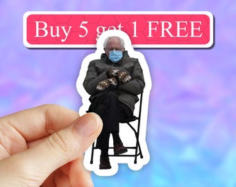 May include: A sticker featuring a photo of a man wearing a blue face mask and a gray jacket, sitting on a folding chair. The sticker has a red banner at the top that says "Buy 5 get 1 FREE".