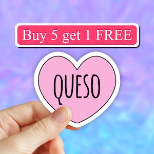 May include: Pink heart-shaped sticker with the word "QUESO" in black lettering. The sticker is being held by a hand. The background is a blurred purple and blue gradient. The text "Buy 5 get 1 FREE" is on a white banner with a pink background.