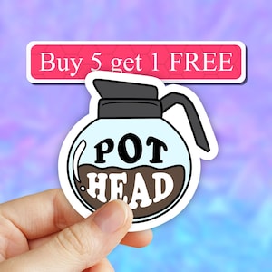 May include: A white coffee pot sticker with the text "POT HEAD" in black lettering. The sticker is held in a hand against a blue and purple background. The text "Buy 5 get 1 FREE" is visible in the background.