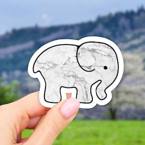 May include: White marble elephant sticker with a black outline. The sticker has a simple, cartoon-like design.