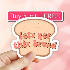 May include: A white bread sticker with the text "lets get this bread" in pink. The sticker has a brown outline and is held in a hand. The text "Buy 5 get 1 FREE" is visible in the background.