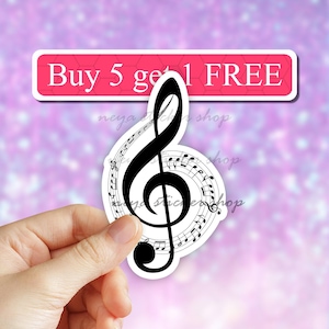 May include: A black and white treble clef sticker with musical notes surrounding it. The sticker is being held by a hand. The text "Buy 5 get 1 FREE" is visible in the background.