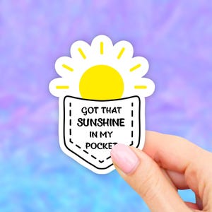 May include: A white sticker with a yellow sun and a black pocket with the text "GOT THAT SUNSHINE IN MY POCKET"