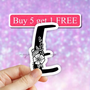 May include: Black and white floral letter E sticker. The letter is outlined in black and has a floral design with white flowers and leaves.