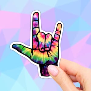 May include: A tie-dye sticker of a hand making the American Sign Language sign for "I love you".