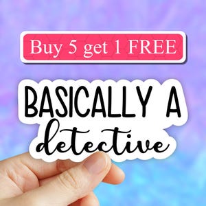 May include: White sticker with black text that reads "BASICALLY A detective". The sticker is being held by a hand. A pink banner above the sticker reads "Buy 5 get 1 FREE".
