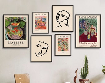 May include: A collection of framed Matisse art prints displayed on a white wall. The prints feature colorful landscapes, abstract faces, and still life compositions. The frames are black, and the prints are in various sizes.