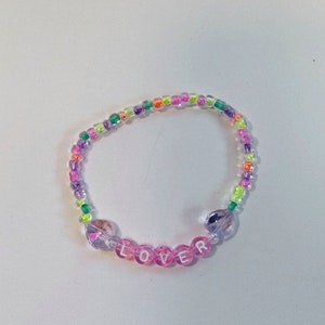May include: A multi-colored beaded bracelet with the word "LOVER" spelled out in pink beads.