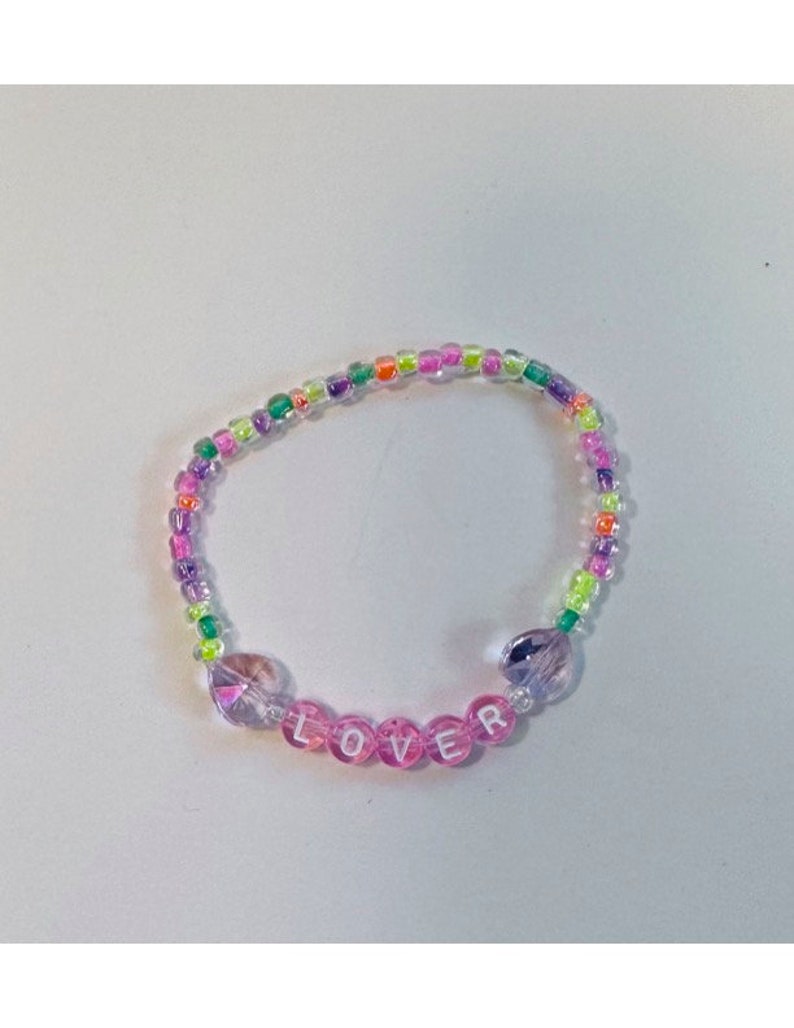 May include: A multi-colored beaded bracelet with the word "LOVER" spelled out in pink beads.