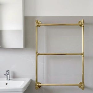 Peut inclure: Un porte-serviettes chauffant doré à trois niveaux, fixé sur un mur de salle de bain carrelé gris. La salle de bain comprend un lavabo blanc, un miroir et une cabine de douche. Le design est moderne et minimaliste.