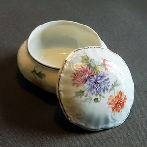 White ceramic candy box with mauve and orange flower patterns.