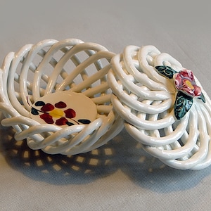 Könnte beinhalten: Weißer Keramikkorb mit Deckel, der Korb ist geflochten und der Deckel hat ein gemaltes Blumendesign.