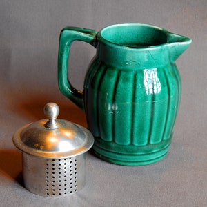 Vintage green ceramic teapot with perforated metal cap.