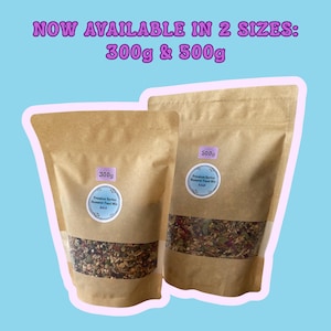 Puede incluir: Dos bolsas de papel marr&oacute;n de comida para h&aacute;mster, una etiquetada con 300g y la otra con 500g. Las bolsas tienen una ventana transparente que muestra el contenido mixto de semillas y granos. El texto "NOW AVAILABLE IN 2 SIZES: 300g & 500g" est&aacute; en la parte superior.