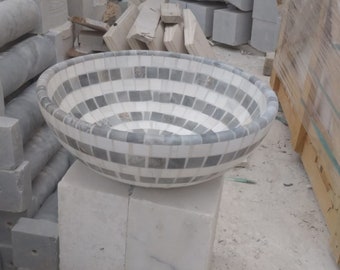May include: A white and gray mosaic sink bowl. The bowl is round and has a slightly curved rim. The mosaic tiles are small and arranged in a spiral pattern.