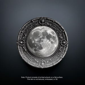 May include: A circular, silver-toned decorative piece featuring a detailed depiction of the moon. The moon image is centered within an ornate, engraved frame. The piece is set against a dark background. Note: Product consists of printed artwork on a flat surface.
