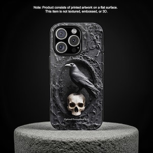 May include: Black phone case featuring a raven perched on a skull within an ornate frame. The case has a dark, textured appearance with the words "Optional Personalized Text" at the bottom. The product consists of printed artwork on a flat surface.