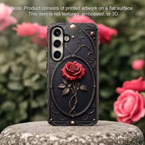 Puede incluir: Una funda de teléfono negra con un diseño detallado y ornamentado que presenta una sola rosa roja. La funda tiene una protuberancia de cámara elevada con tres lentes de cámara.