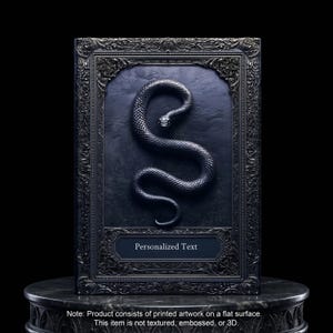 Peut inclure: Un cadre noir rectangulaire avec une bordure ornée et un panneau central sombre présentant l'image imprimée d'un serpent noir enroulé. Sous le serpent, une étiquette rectangulaire porte le texte imprimé en blanc Personalized Text.