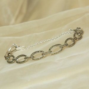 May include: A silver chain bracelet with oval links set with marcasite stones.