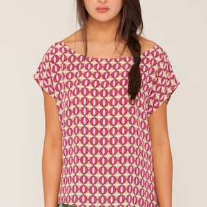 May include: A pink and white geometric print top with a short sleeve and a slightly asymmetrical hemline. The top is made of a lightweight fabric and has a relaxed fit.