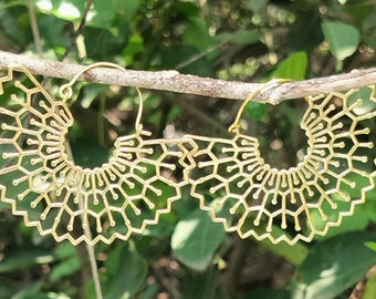 Peut inclure: Une paire de boucles d'oreilles créoles dorées avec un motif géométrique délicat et complexe. Les boucles d'oreilles sont en métal et ont une forme circulaire.