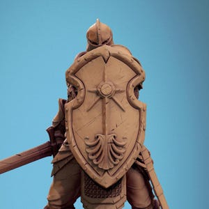 May include: A brown plastic miniature figurine of a knight wearing armor and holding a sword and shield. The shield has a sunburst design and the knight is standing on a rocky base.