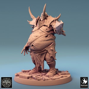 May include: A detailed miniature figure of a grotesque, fleshy, armored creature with a horned helmet and a shield. The figure is painted in a light brown color and stands on a rocky base.