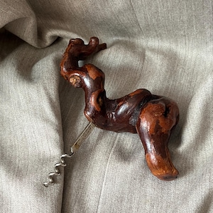 Può includere: Un cavatappi in legno fatto a mano con una forma organica unica. Il legno marrone scuro è lucido e il cavatappi in metallo è argentato. Progettato per aprire bottiglie di vino.