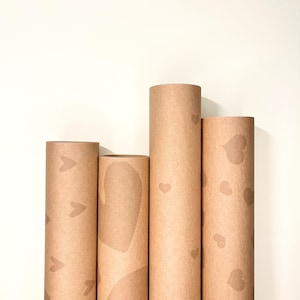 Vier Kraftpapier-Geschenkpapierrollen nebeneinander stehend mit dezenten Ton-in-Ton Herzmustern in neutralen Brauntönen – handgefertigtes romantisches Geschenkpapier aus hochwertigem Papier für Partner, minimalistisches elegantes Design