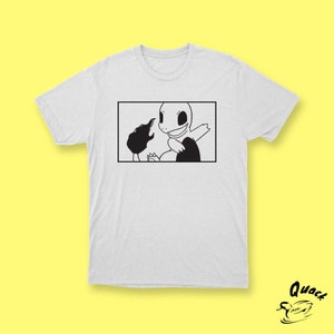 Puede incluir: Camiseta blanca con un gráfico en blanco y negro de un personaje de dibujos animados. El personaje es una criatura reptiliana con una boca grande y dientes afilados. El personaje está sosteniendo una criatura redonda más pequeña en su boca.