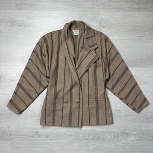 May include: A brown blazer with vertical black stripes. The blazer has a double-breasted design with two gold-colored buttons and two front pockets. The jacket has a notched lapel and long sleeves.