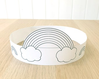 May include: A white paper crown with a black outline of a rainbow and clouds. The crown is designed to be worn as a headband.