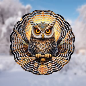 May include: A metal wind spinner with a detailed design of an owl with golden eyes and brown feathers. The owl is surrounded by intricate swirling patterns in shades of gold, black, and silver.