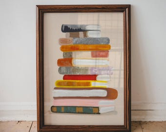 Könnte beinhalten: Ein gerahmtes Kunstwerk mit einem Stapel bunter Bücher. Die Bücher haben verschiedene Farben, darunter Orange, Rot, Rosa und Grün, mit sichtbaren Buchrücken. Der Rahmen ist dunkelbraun und der Hintergrund ist ein neutrales Beige.