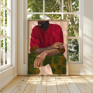 Puede incluir: Impresi&oacute;n art&iacute;stica enmarcada que representa una figura sentada con una camisa roja y pantalones verdes estampados. La obra de arte tiene una paleta de colores c&aacute;lidos, con los brazos cruzados. El fondo es rosa p&aacute;lido.