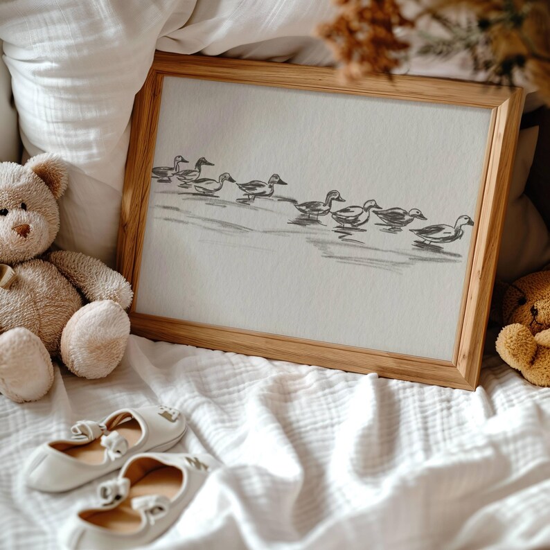 May include: A framed black and white drawing of a line of ducks swimming in a row. The drawing is on a white background and is framed in a light wood frame.