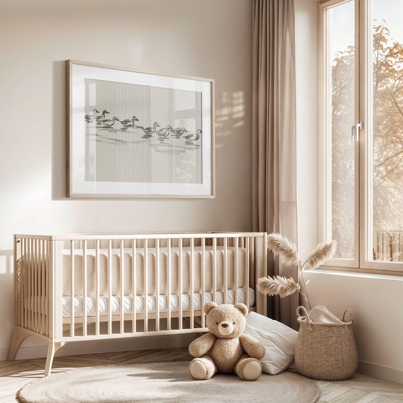 May include: A light wood crib with a white mattress and a beige and white striped fitted sheet. A brown teddy bear sits on the floor in front of the crib. A wicker basket with a white blanket sits on the floor next to the crib. A large framed print of a flock of birds in flight hangs on the wall above the crib.
