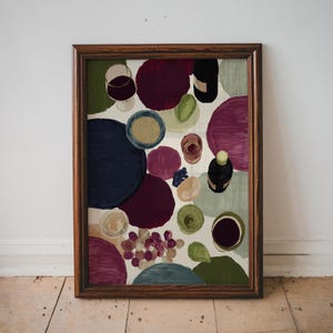 Pode incluir: Uma impressão artística emoldurada com uma natureza morta de comida e bebida. A obra de arte inclui taças de vinho, uma garrafa de vinho, uvas e outros elementos dispostos em formas abstratas coloridas. A moldura é de cor castanho escuro.