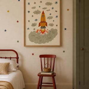 May include: A framed wall art print featuring a yellow and orange rocket ship launching into a sky filled with gray clouds and small multi-colored stars. The rocket has a circular window and emits orange and yellow flames from its base.